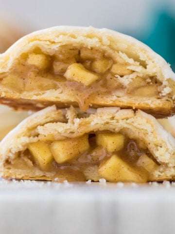 Apple hand pie cut in half and stacked on top of itself showcasing the flaky pastry dough and juicy apple filling.