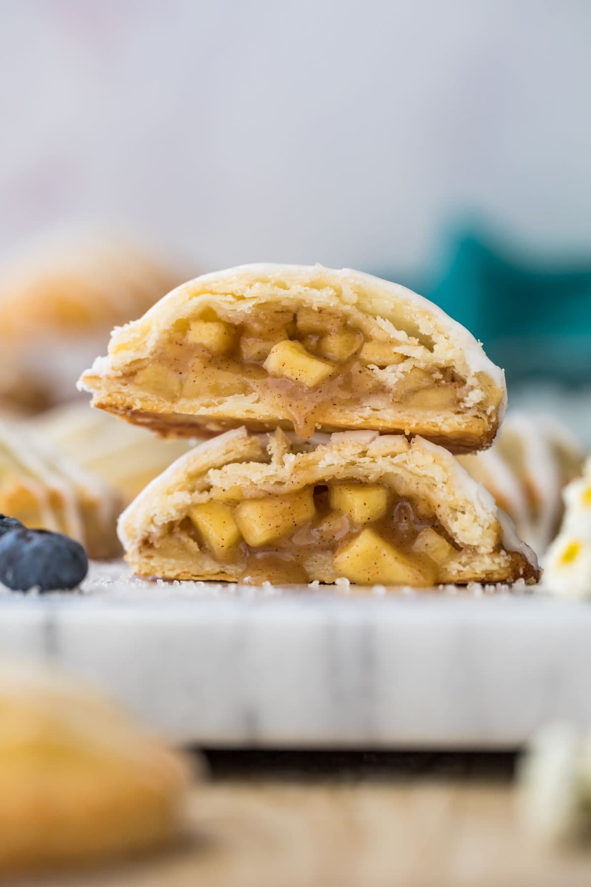 Apple hand pie cut in half and stacked on top of itself showcasing the flaky pastry dough and juicy apple filling.