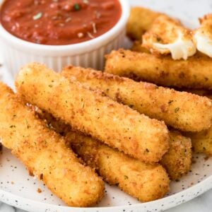 Homemade mozzarella sticks and marinara sauce on plate.