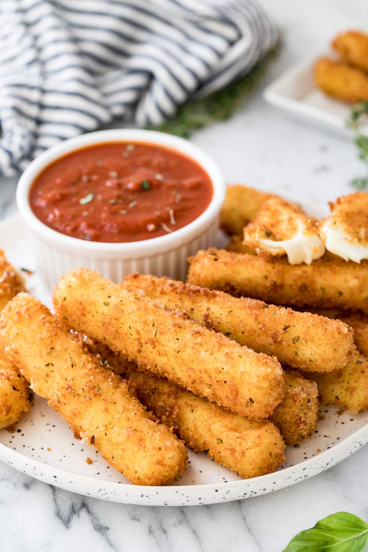 Homemade mozzarella sticks and marinara sauce on plate.