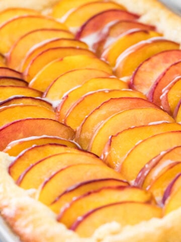 Close-up view of peach cake topped with sliced peaches in jellyroll pan