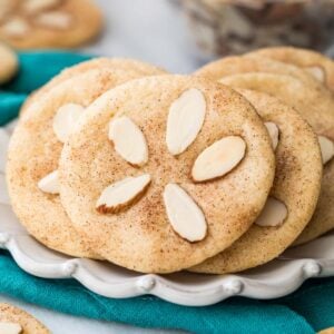 Cookies decorated with almond slivers to look like sand dollars on white plate