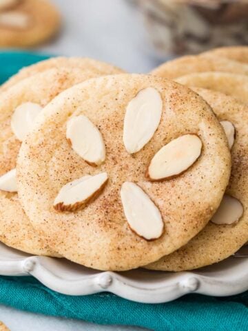 Cookies decorated with almond slivers to look like sand dollars on white plate