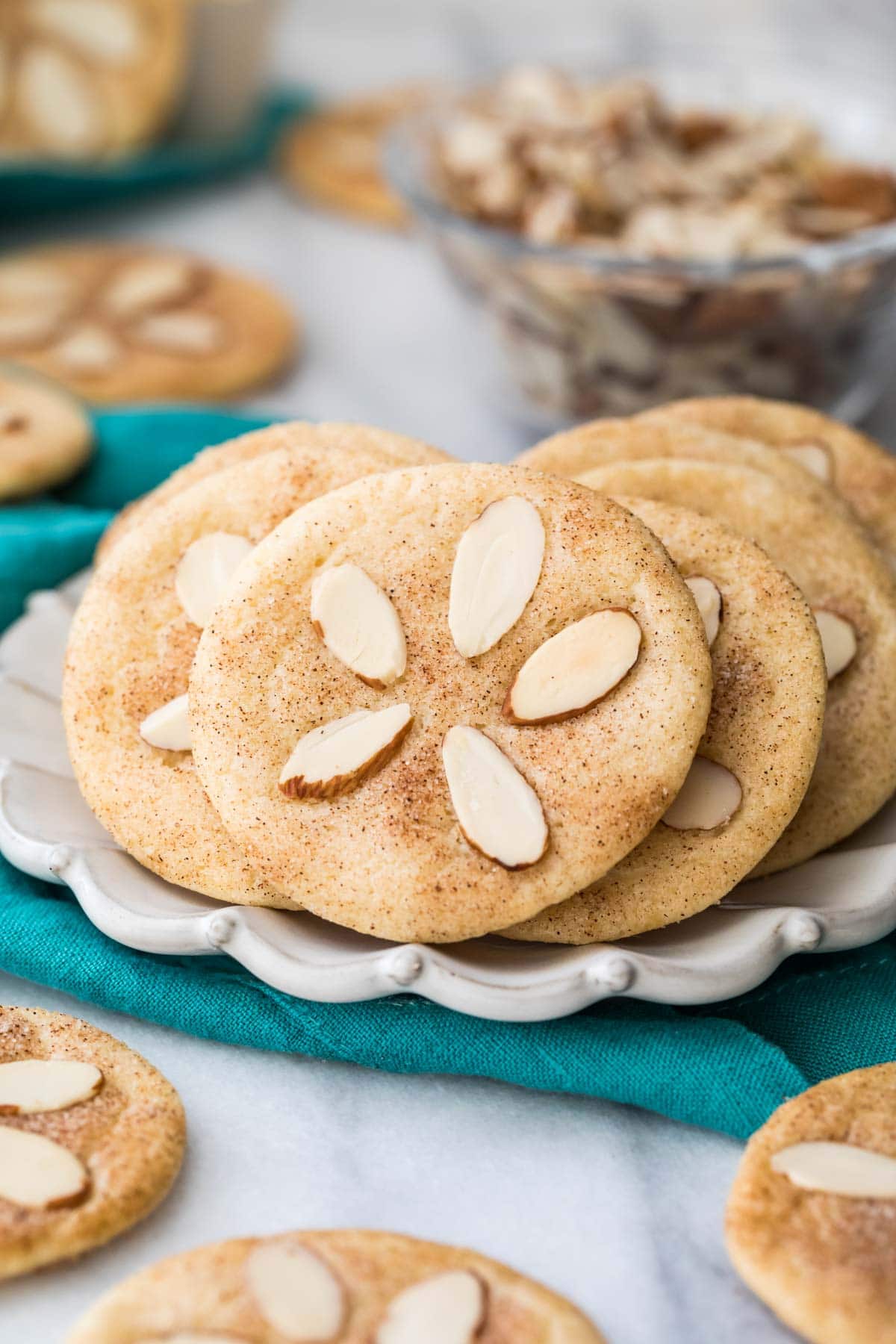 Cookies decorated with almond slivers to look like sand dollars on white plate