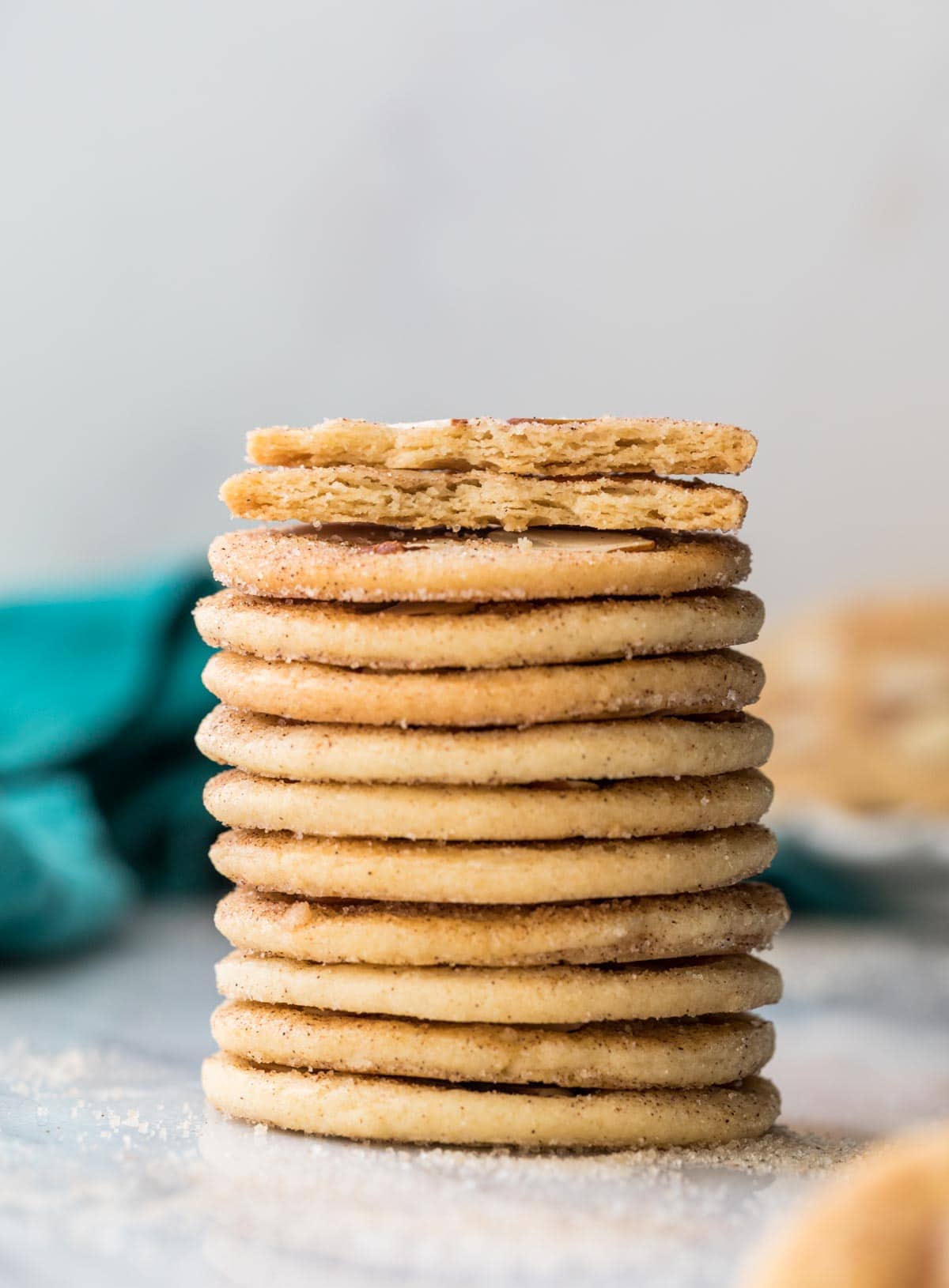 Stack of sand dollar cookies with cookie broken in half on top, showing that they are thin, crispy, and flat cookies