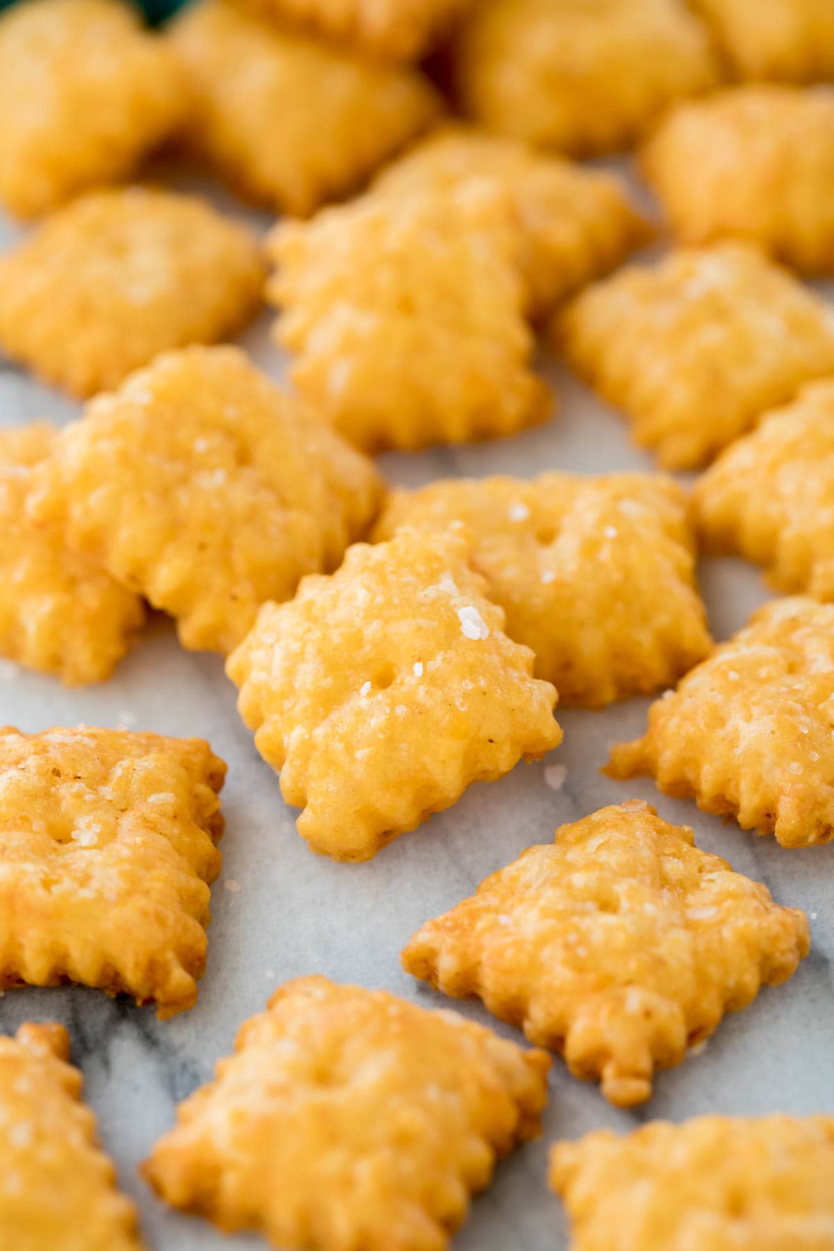 Zoomed-in view of homemade cheese crackers with frilled edges and topped with sea salt