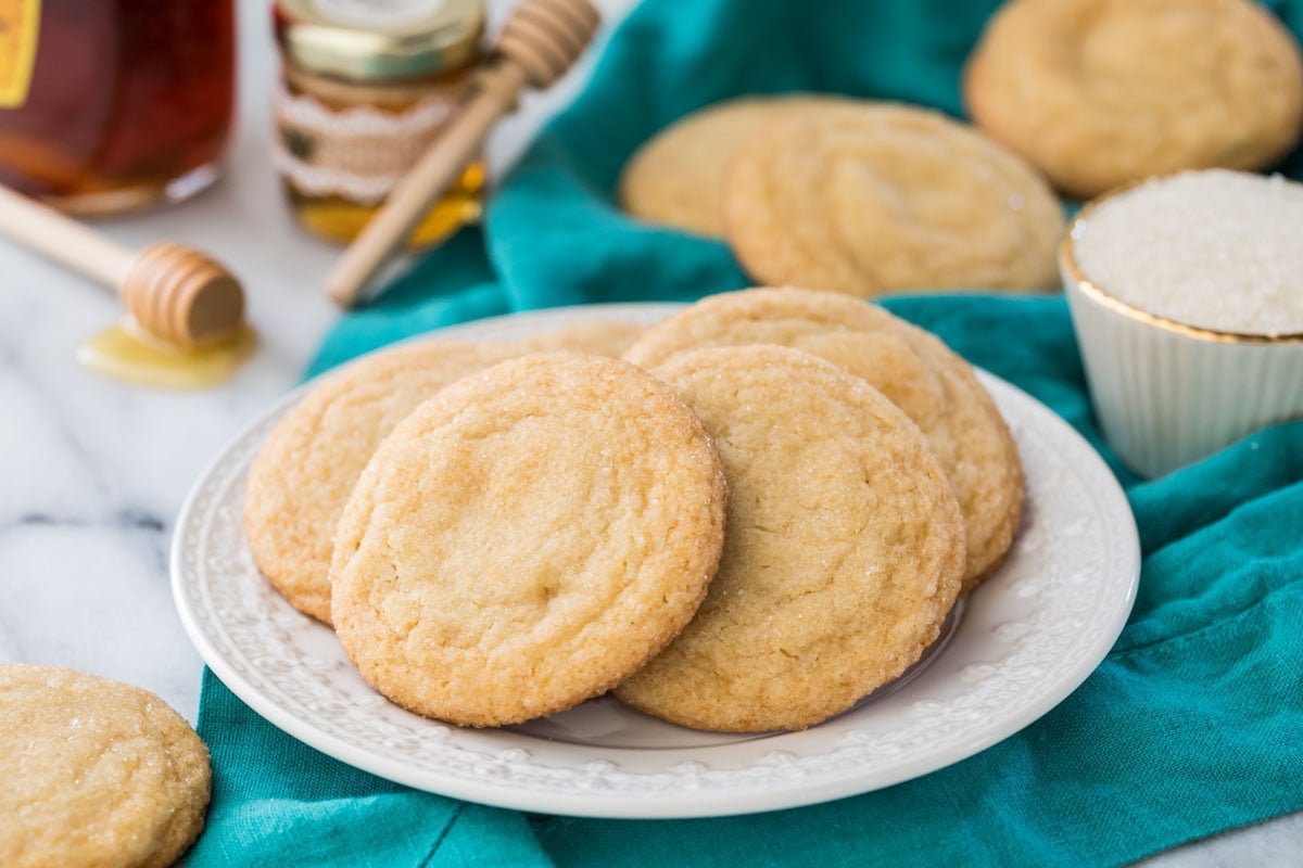 horizontal photo of honey cookies on a white plate with teal linen in background
