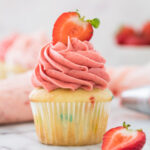 yellow cupcake with pink strawberry frosting swirled on top