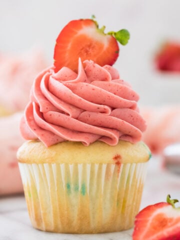 yellow cupcake with pink strawberry frosting swirled on top