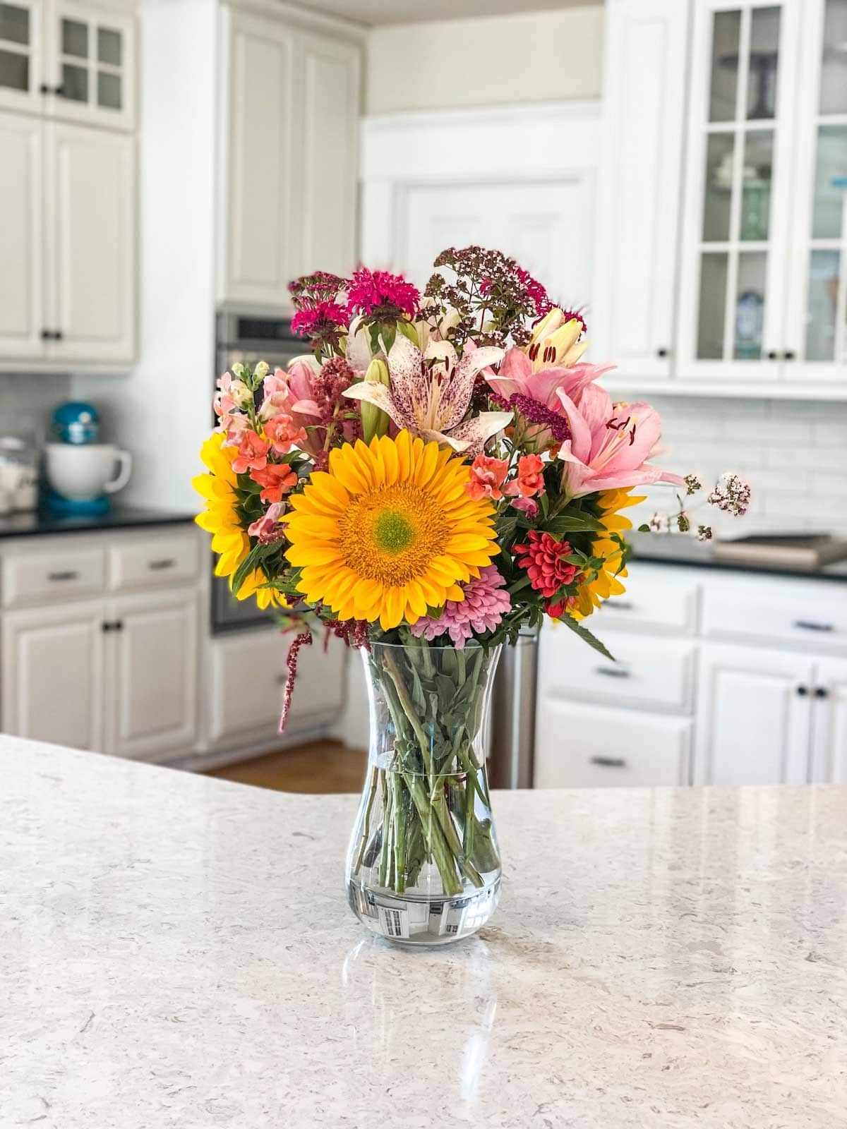 Glass vase with an array of multicolored flowers on white countertop