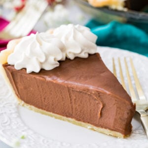 slice of chocolate pie topped with whipped cream on white plate with fork