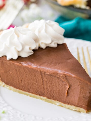 slice of chocolate pie topped with whipped cream on white plate with fork
