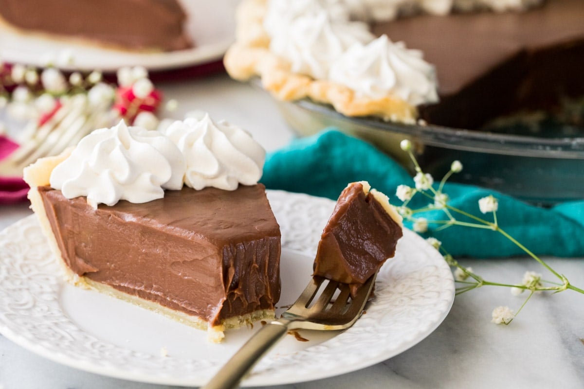 Slice of chocolate pie and fork with bite sitting on white plate