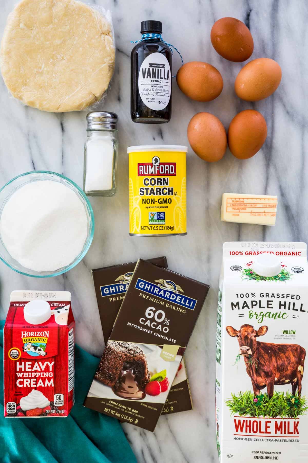 overhead view of white marble countertop neatly covered with with ingredients for making chocolate pie