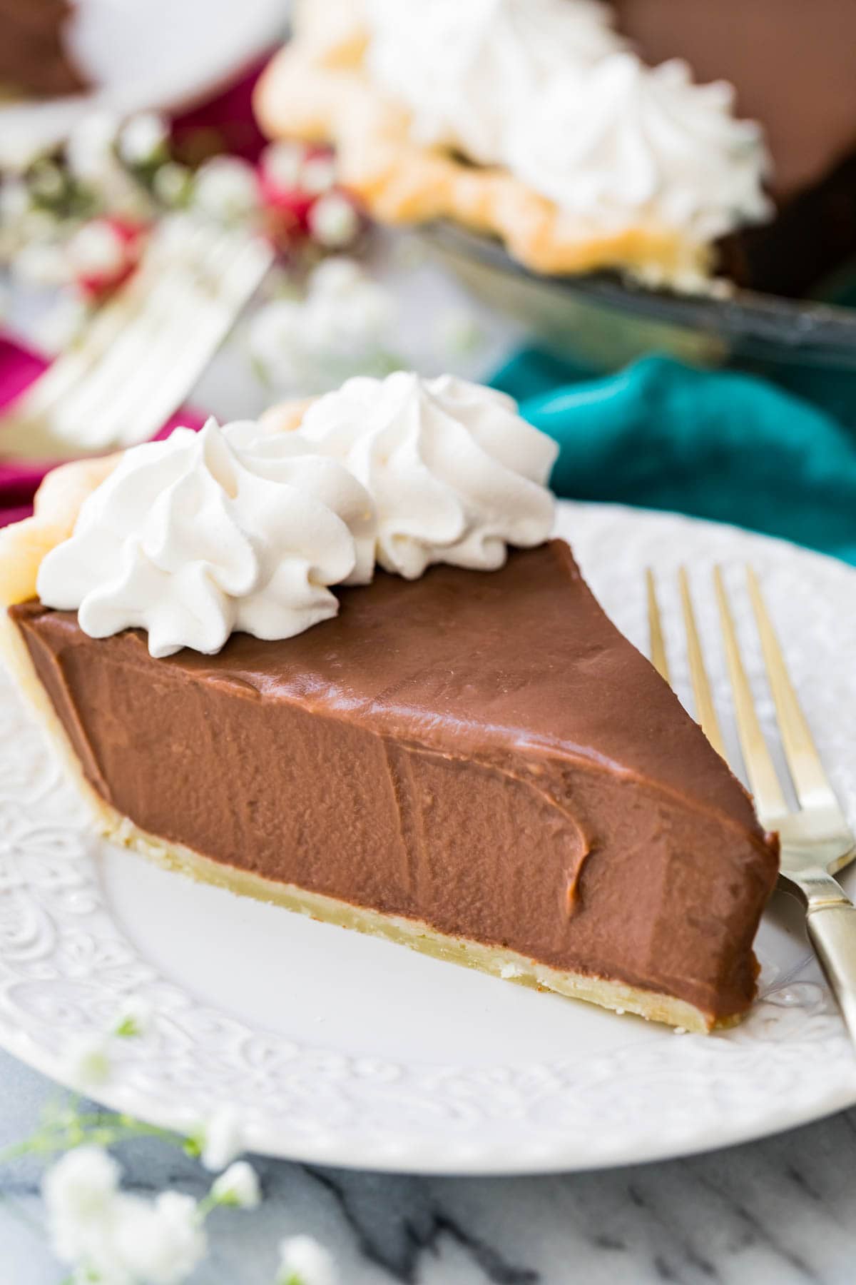 slice of chocolate pie topped with whipped cream on white plate with fork