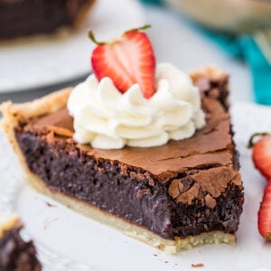 slice of chocolate chess pie topped with whipped cream and a strawberry with one bite missing