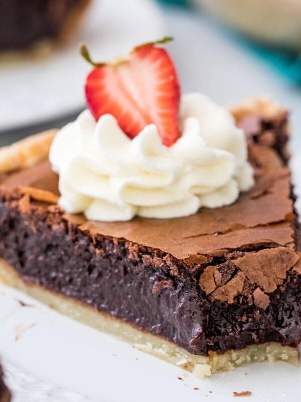 slice of chocolate chess pie topped with whipped cream and a strawberry with one bite missing