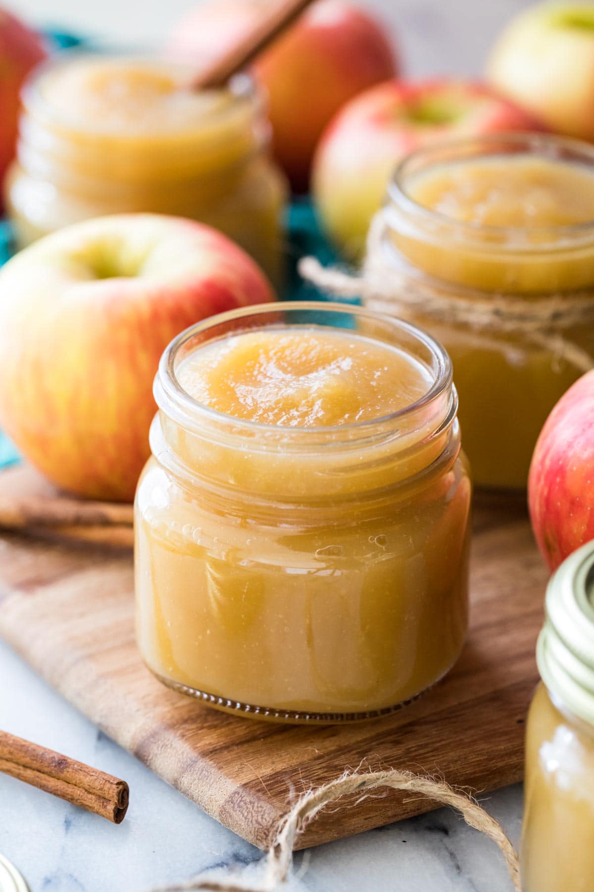 Clear glass jars filled with golden colored applesauce with red apples intermingled