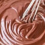 thick and shiny chocolate ganache being stirred with whisk