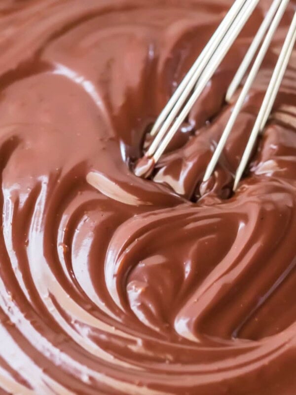 thick and shiny chocolate ganache being stirred with whisk