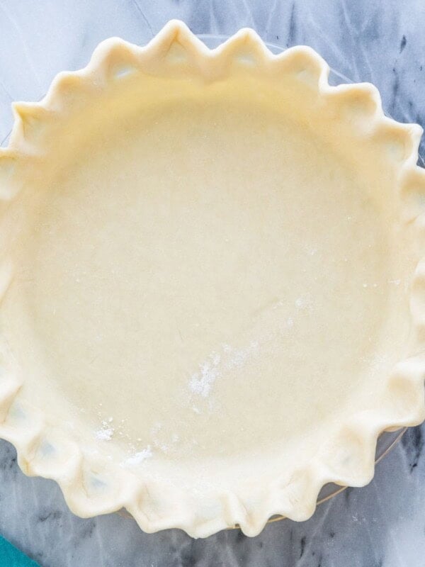 Overhead view of unbaked homemade pie crust with fluted edge on gray marble countertop