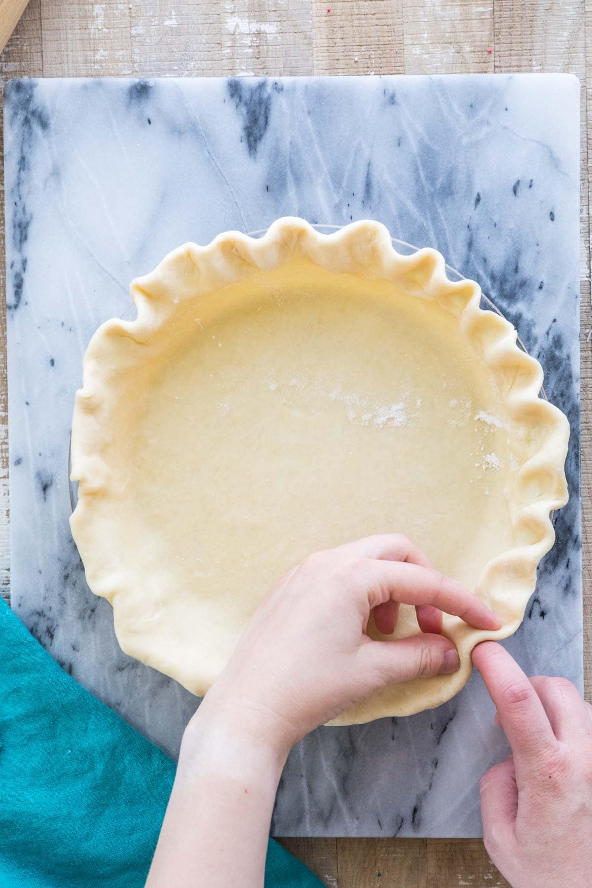 homemade pie crust with edges being fluted by hand