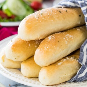 stack of golden brown homemade breadsticks dusted with herbs and parmesan cheese