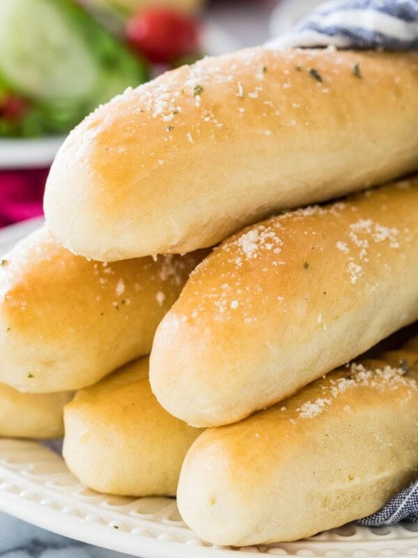 stack of golden brown homemade breadsticks dusted with herbs and parmesan cheese