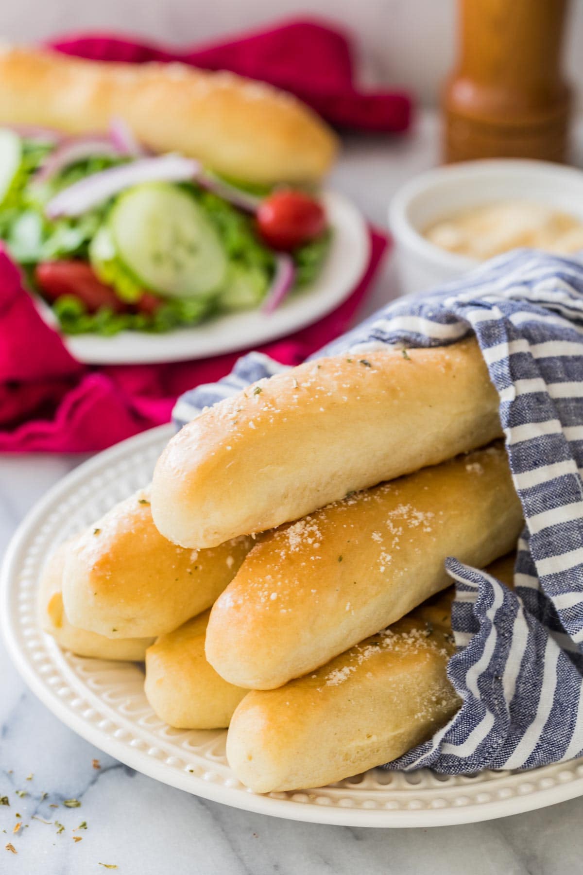 plate of homemade breadsticks draped in linen towel