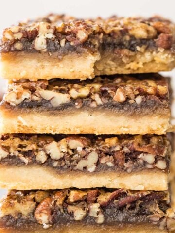 four pecan pies stacked on top of each other, with the top bar missing one bite