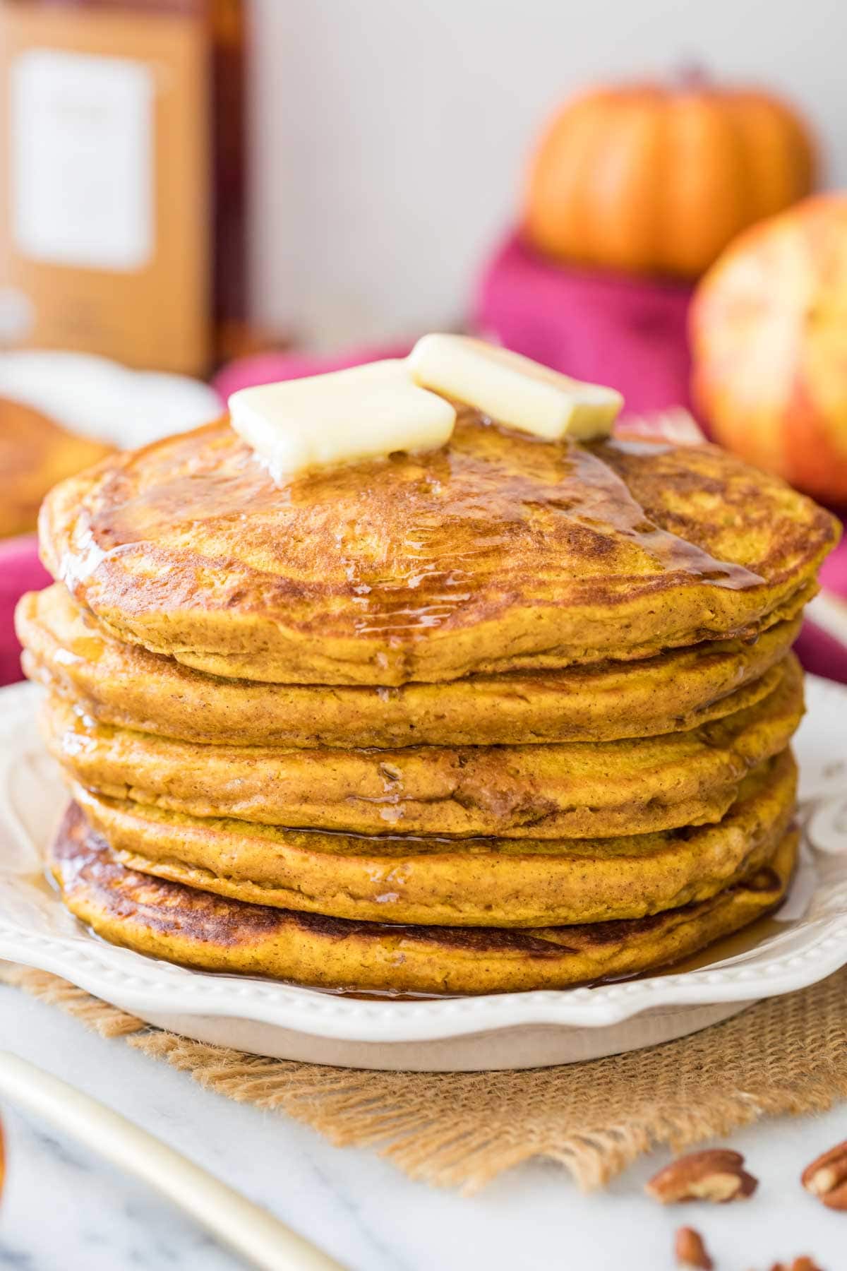 stack of pumpkin pancakes drizzled with maple syrup and topped with butter