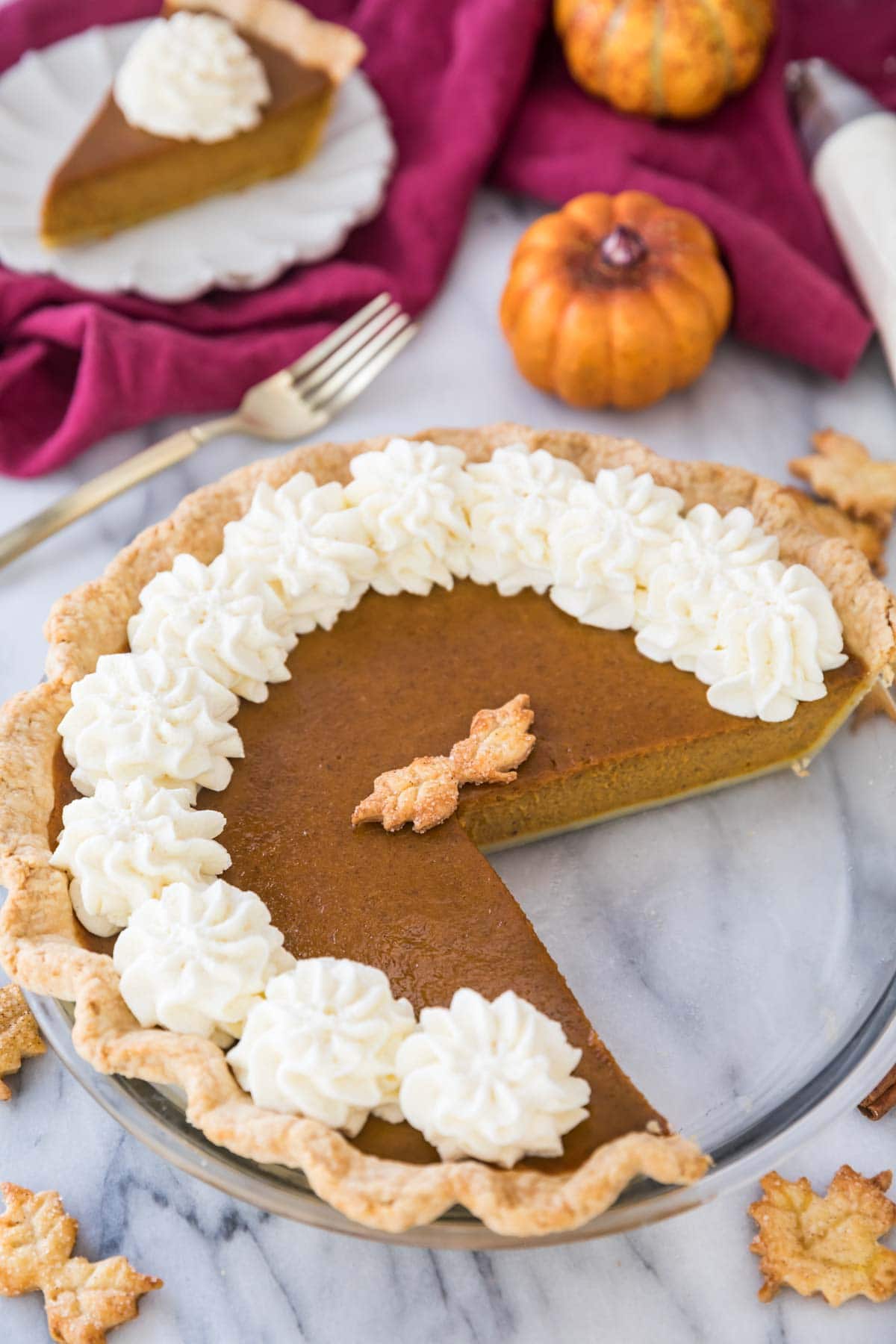 overhead view of pumpkin pie topped with a whipped cream border with several slices missing