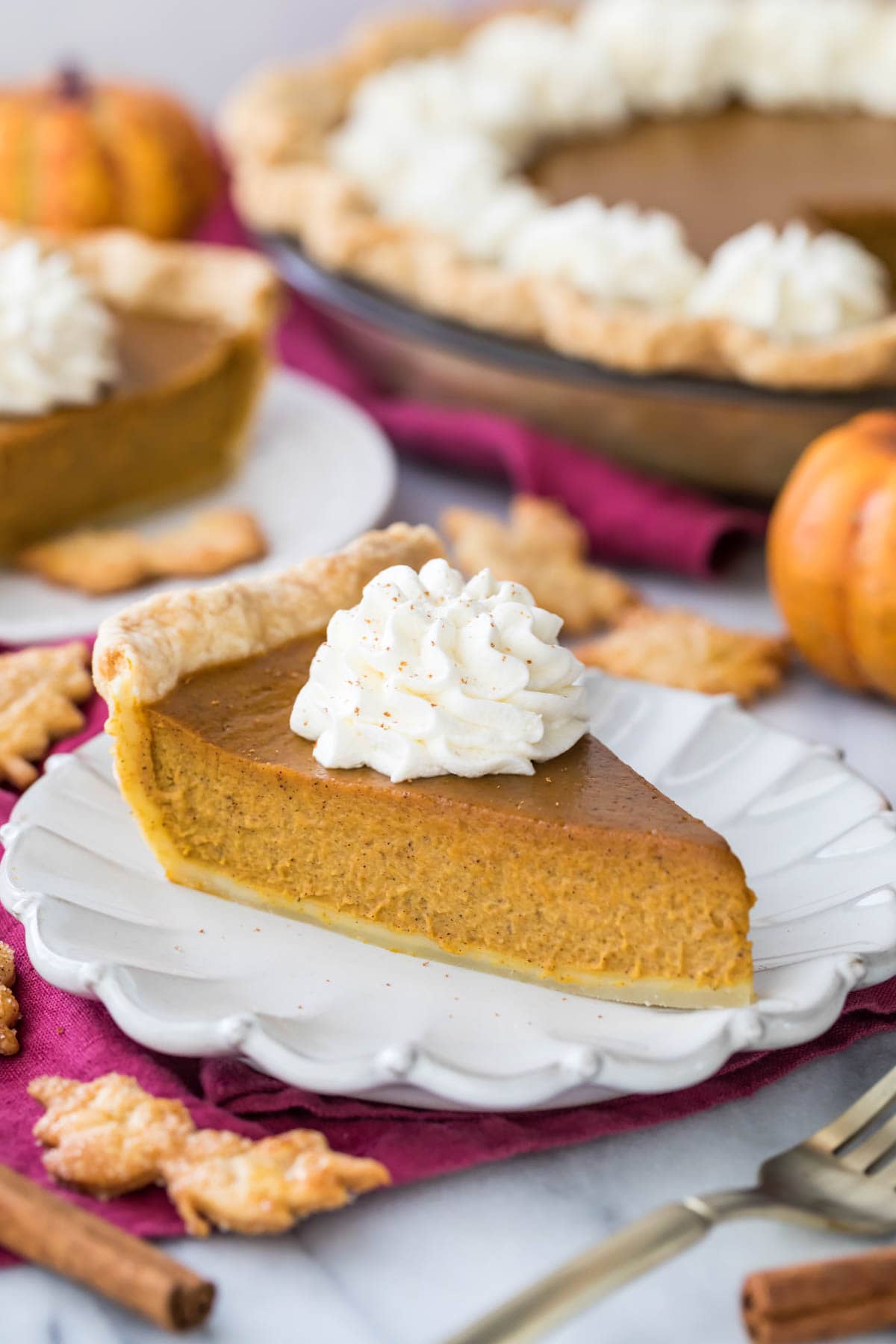 side view of a slice of pumpkin pie topped with a dollop of whipped cream