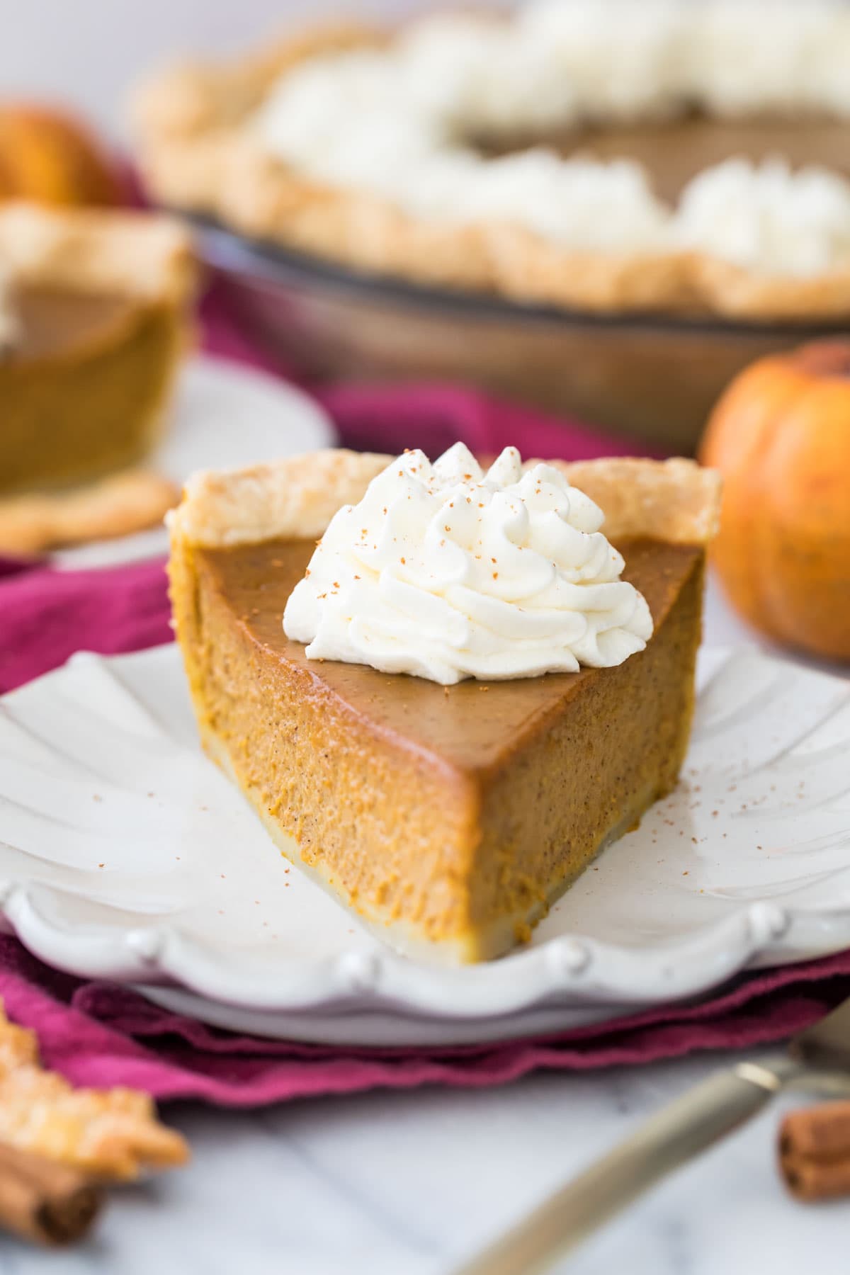 Head-on view of a pumpkin pie slice topped with a piped swirl of whipped cream