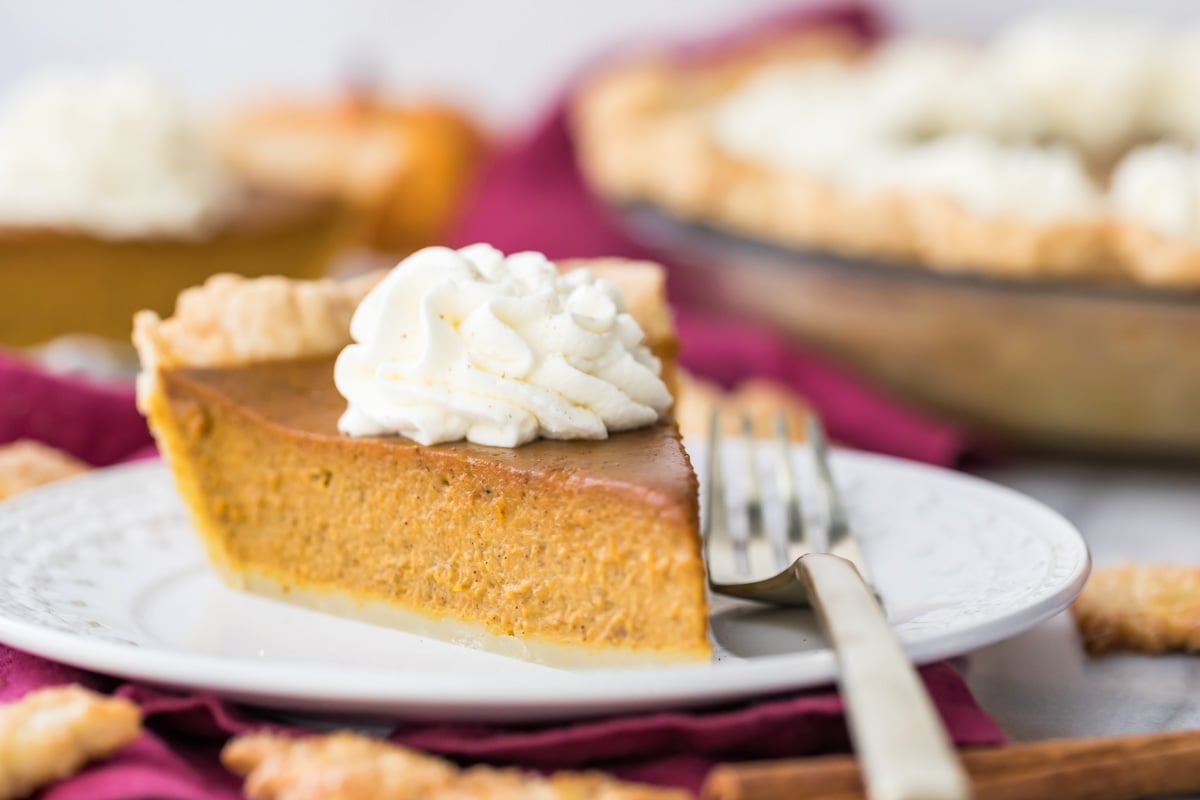 slice of pumpkin pie on white plate with fork