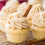 snickerdoodle cupcake with cinnamon stick garnish surrounded by other cupcakes