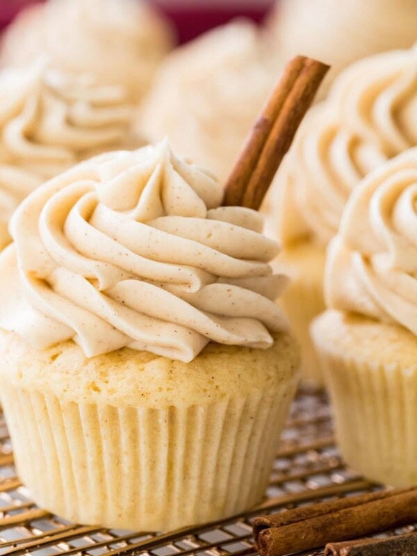 snickerdoodle cupcake with cinnamon stick garnish surrounded by other cupcakes