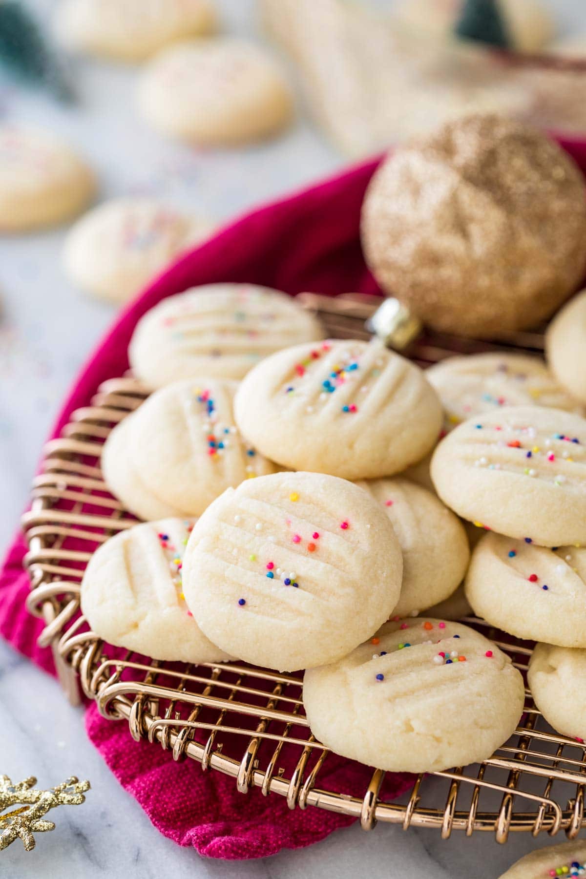 whipped shortbread cookies on gold cooling rack with red towel underneath