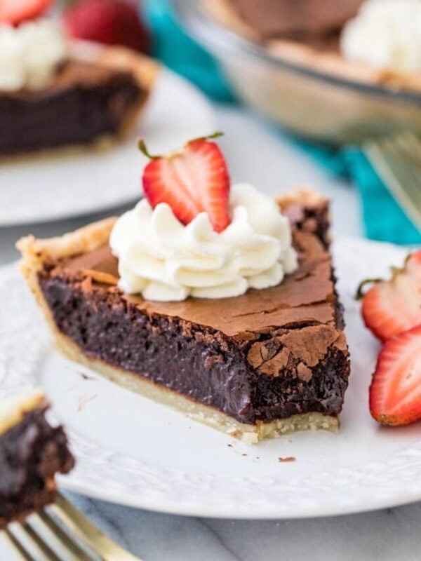 slice of chocolate chess pie topped with whipped cream and a strawberry with one bite missing