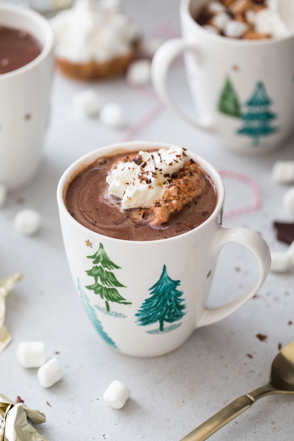 white mug of hot chocolate topped with whipped cream and chocolate shavings