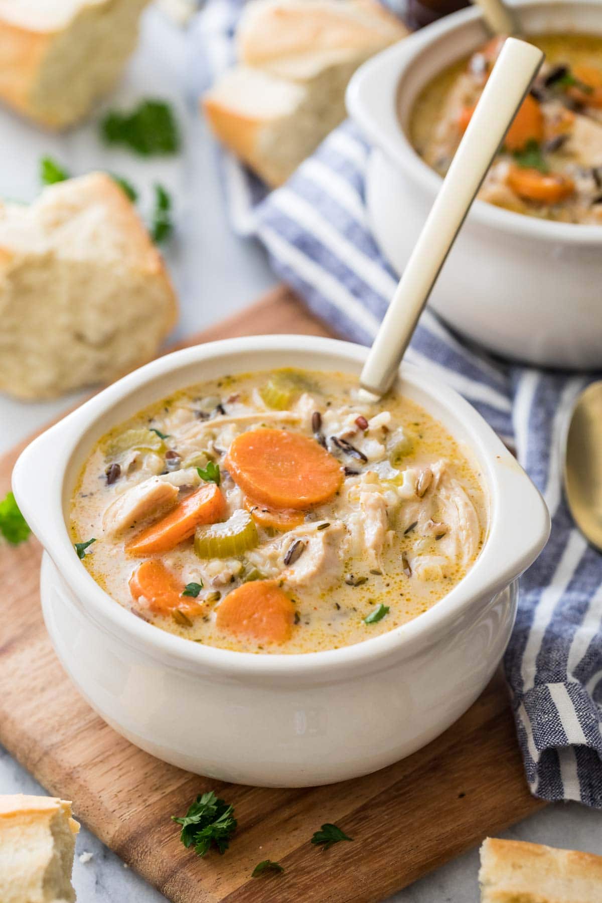 white bowls of chicken and rice soup served with bread