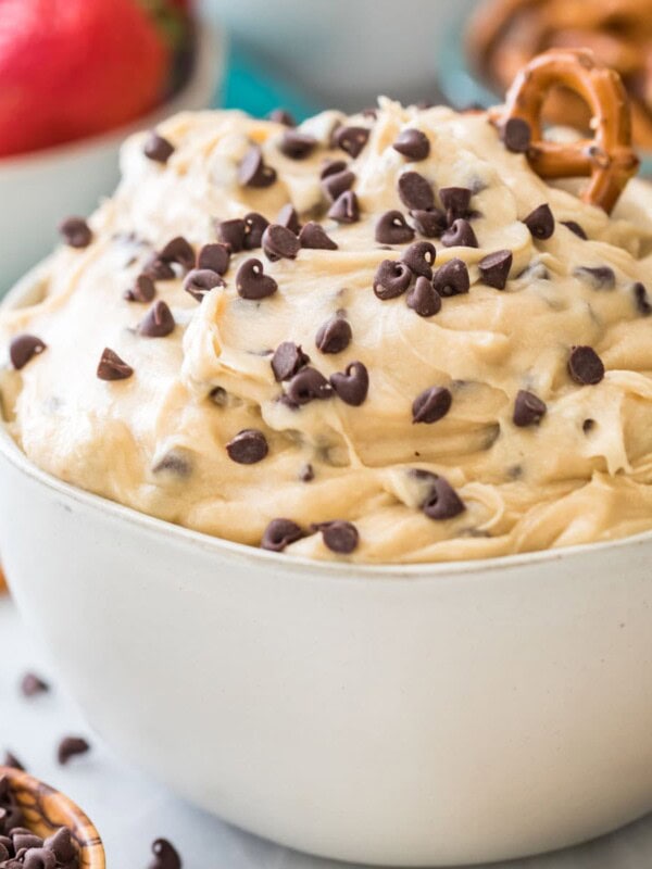 bowl of cookie dough dip topped with mini chocolate chips and a pretzel