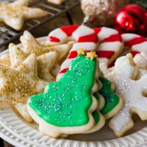 plate of iced and decorated sugar cookies neatly arranged according to type, including christmas trees, gold stars, candy canes, and snowflakes