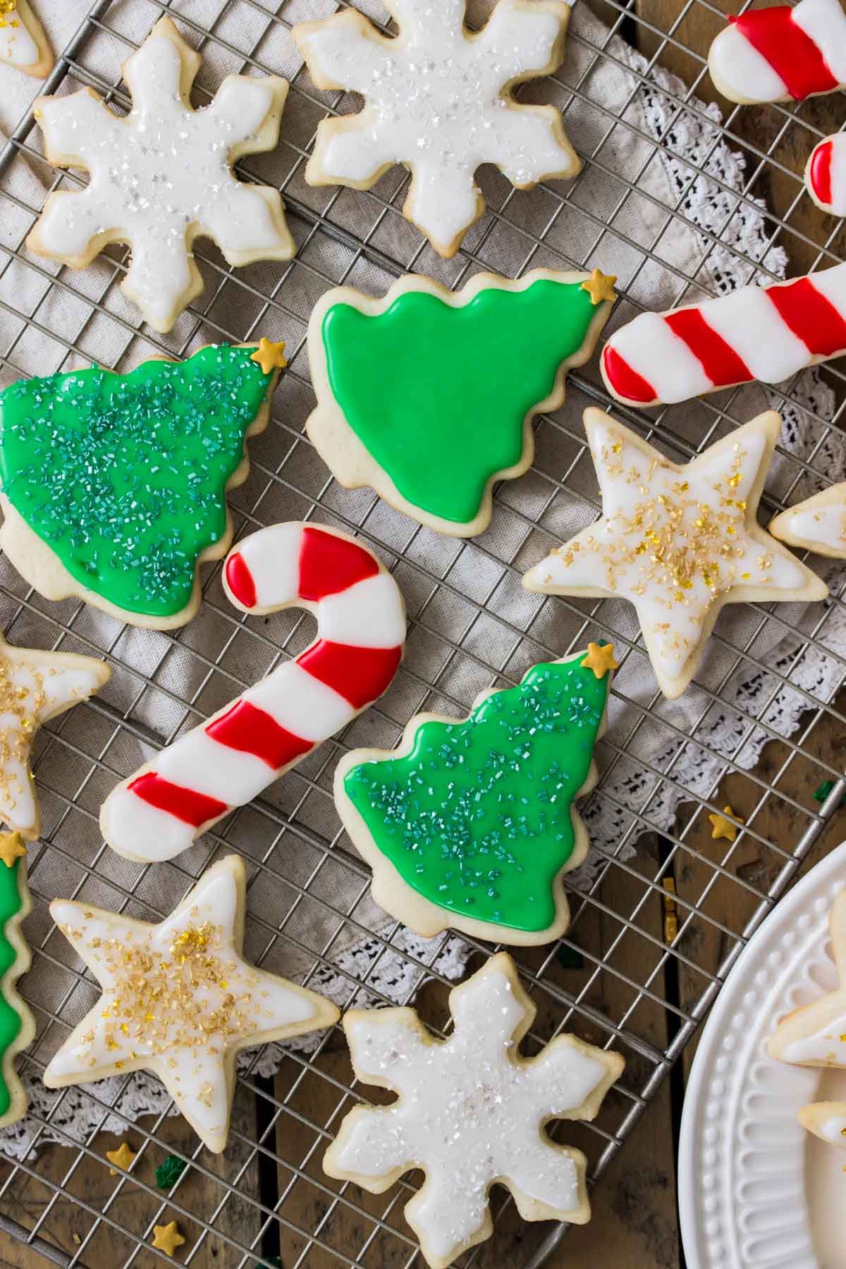 iced christmas sugar cookies on metal cooling rack, including snowflakes, christmas trees, candy canes, and stars