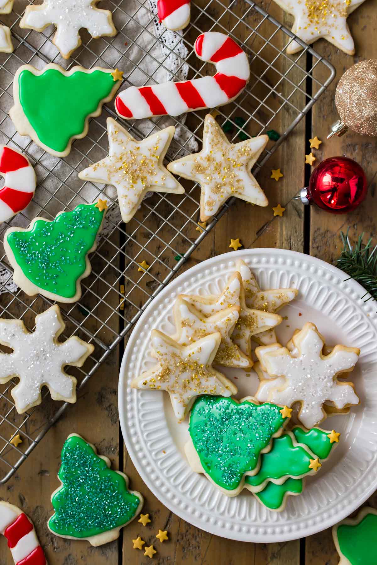 christmas themed sugar cookies on cooling rack and white plate