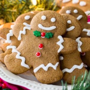 White plate of decorated gingerbread men surrounded by Christmas lights and evergreen