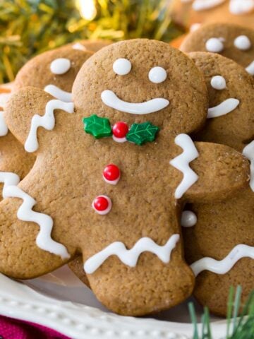 White plate of decorated gingerbread men surrounded by Christmas lights and evergreen