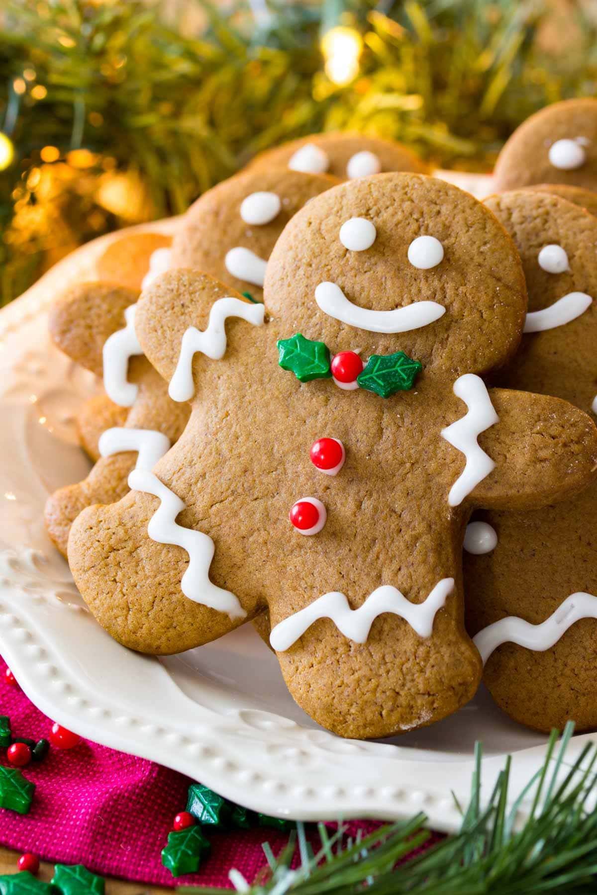 White plate of decorated gingerbread men surrounded by Christmas lights and evergreen