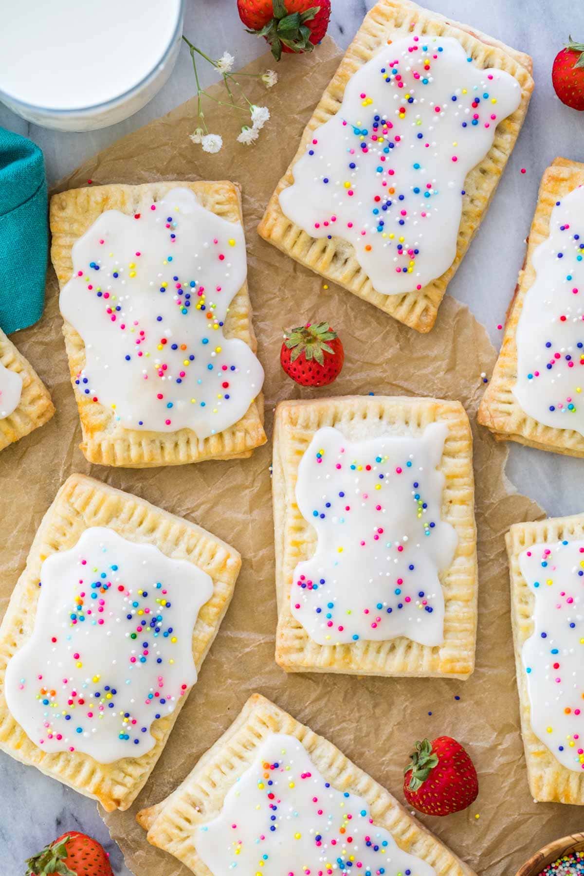 homemade strawberry pop tarts frosted and topped with sprinkles on brown parchment paper