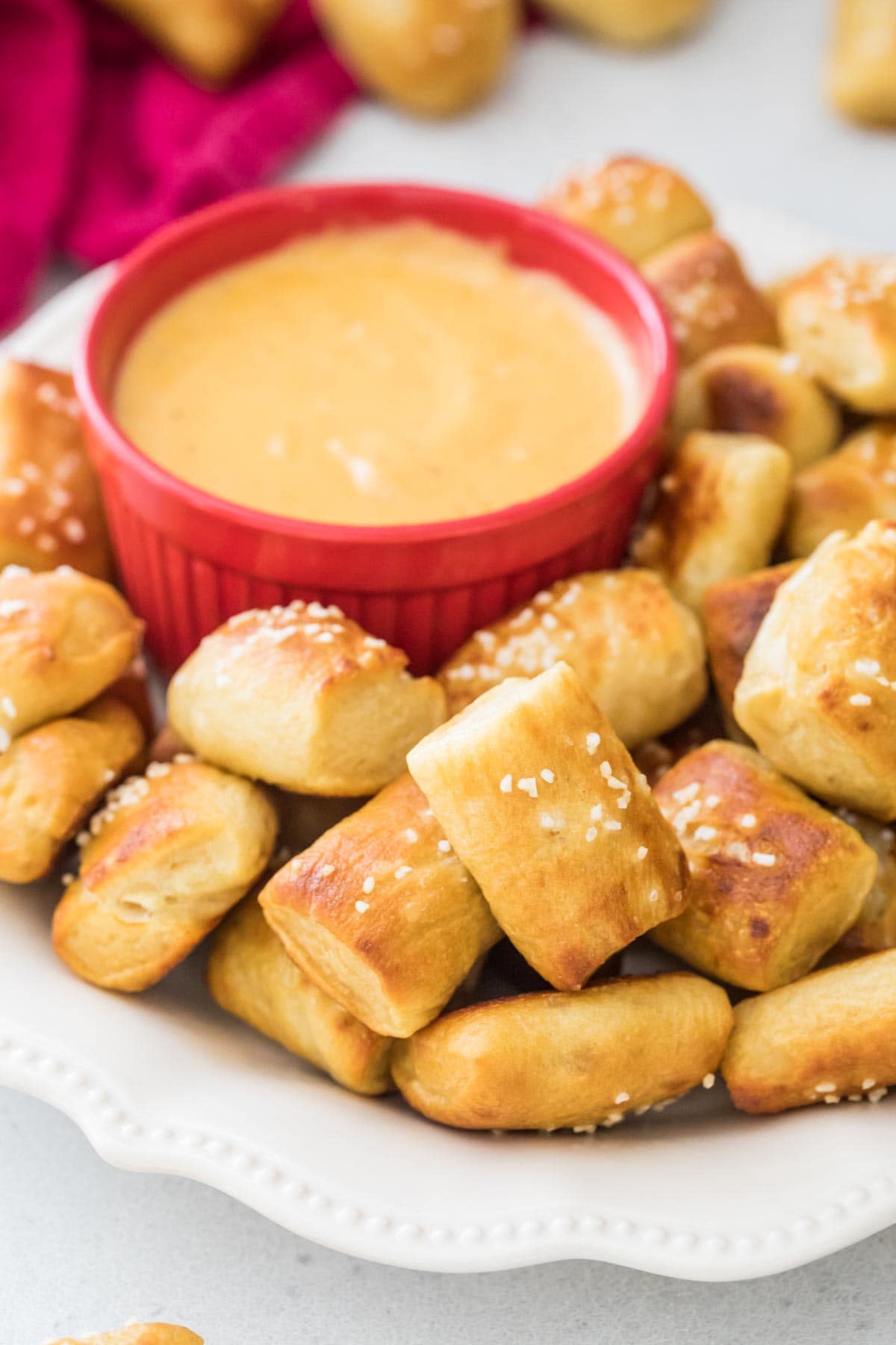 soft pretzel bites on white plate served with a dish of melted cheese for dipping